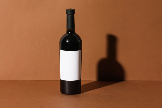 Bottle of wine with blank label on color background. Mockup for design
