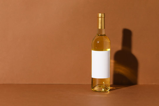 Bottle of wine with blank label on color background. Mockup for design