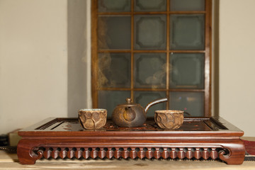 Chinese teapot and cups on a vintage wooden table among a cloud of brown steam