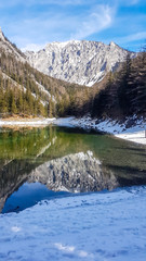 Winter landscape of Austrian Alps with Green Lake in the middle. Powder snow covering the mountains and ground. Emerald color of water. Soft reflection of Alps in calm lake's water. Winter wonderland