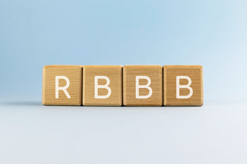 Abbreviation RBBB on wood cubes on blue background. Right bundle branch block. Heart abnormality....