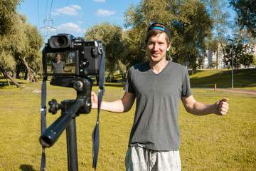 A young blogger records a video blog in a park on a sunny day. Freelancer, consulting, training,...