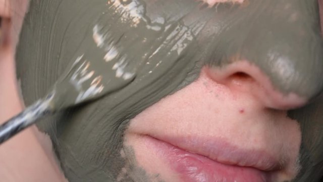 Woman applying green clay mask on the face