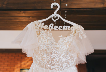 Beautiful white, lace dress of the bride hanging on a hanger close-up.