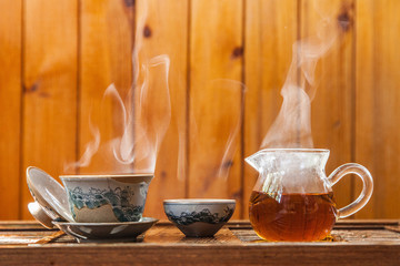 Chinese tea cup and glass kettle  with cloud of vapor on wooden background