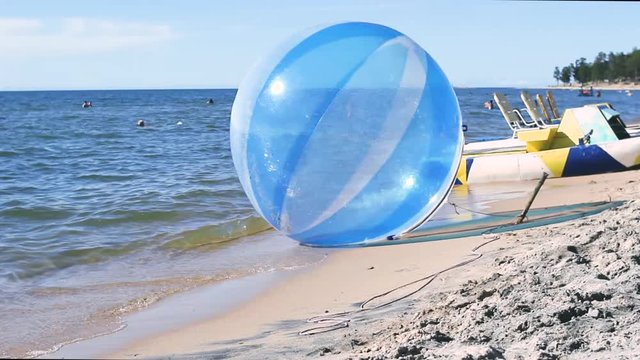 An empty water ball called a zorb or aquasphere, with other water activities, splashes on the waves, Zorbing extreme attraction for beach vacationers
