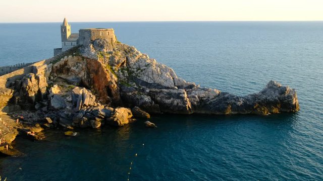 pan over landmark "golfo dei poeti" and st. peter church in Porte Venere, a small italian town. Creative camera movement and perspective from behind rocks