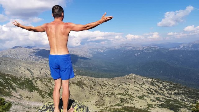 man stands on top of a mountain with open hands. at the top of the mountain, a man with his arms spread wide.