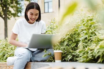 Asian woman sitting outdoors using laptop computer