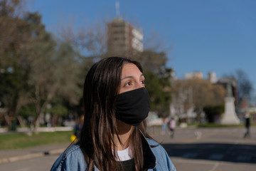 Joven con barbijo por el parque hablando por celular