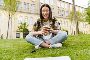 Young asian woman using laptop computer and drinking coffee
