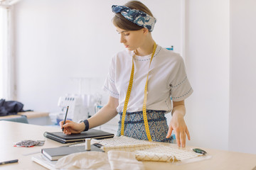 Beautiful young dressmaker working in atelier. Small business/entrepreneur concept.