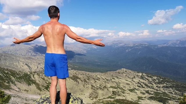 man stands on top of a mountain with open hands. at the top of the mountain, a man with his arms spread wide.