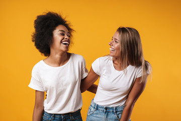 Fototapeta premium Multiracial girls friends isolated over yellow wall background