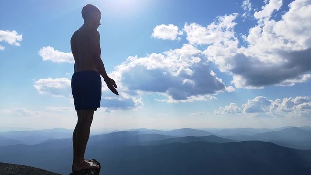 man stands on top of a mountain with open hands. at the top of the mountain, a man with his arms spread wide.