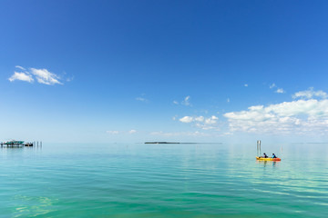 Kayakers paddle across a calm turquoise ocean under a blue sky on a beautiful Summer day in Key Largo, Florida