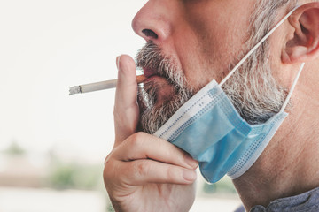 covid-19,Close-up of man with medical mask smoking a cigarette at the street 