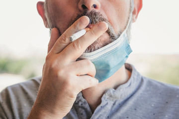 covid-19,Close-up of man with medical mask smoking a cigarette at the street 