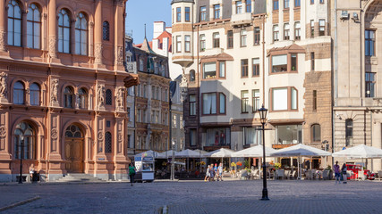 Fototapeta premium Riga. Buildings and cozy streets of the old city. Variegated facades, stone paving stones. Cafes and restaurants. People walk the streets in the evening. Latvia. Summer 2020