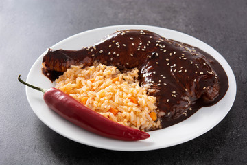 Traditional mole Poblano with rice in plate on black slate background