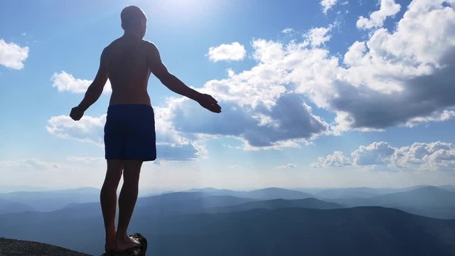 man stands on top of a mountain with open hands. at the top of the mountain, a man with his arms spread wide.