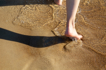 Walking along the shore. Barefoot on the water. Sandy seashore. Sea water. Footprints on the shore. Sand and clear water. Summer at sea