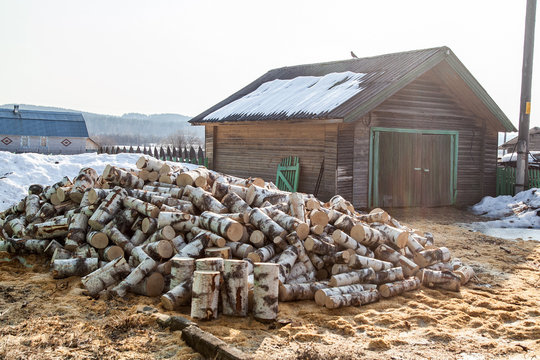 Pile of brich firewood near wooden garage