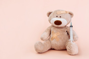 Stuffed Bear animal with syringe isolated on pink background. Children doctor theme.