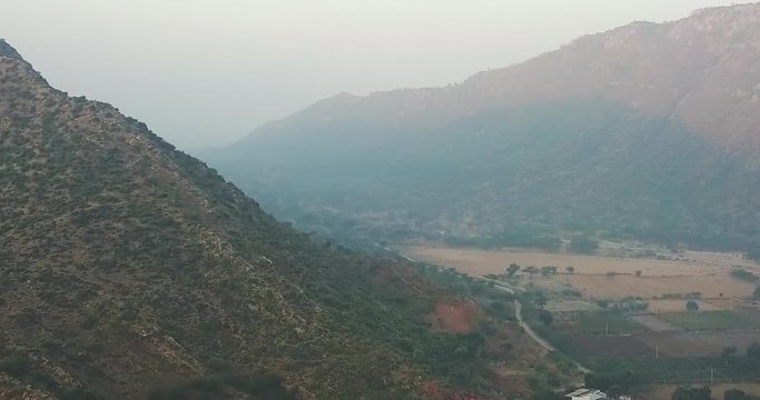 Scenic View Of The Lush Nag Pahar Mountain In Pushkar, India With Temples At The Base On A Misty Day - aerial drone