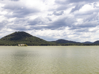 View of the lake surface, hills, clouds in windy weather