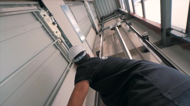 Young man mechanic engineer working doing maintenance on elevator lift at construction site slow motion