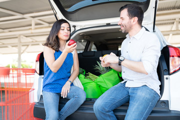 Couple Having Fruits After Loading Groceries In Car