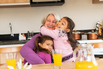 Happy latin grandmother and granddaughters spending good time together at kitchen table, inside. Unity, happiness, affection, love, care concept.