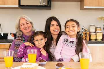 Portrait of female multigenerational family at breakfast table smiling with broad smile in kitchen home, indoors. Togetherness, multi-generation family, support concept.