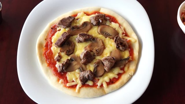 small personal size ham and mushroom pizza served on a white plate