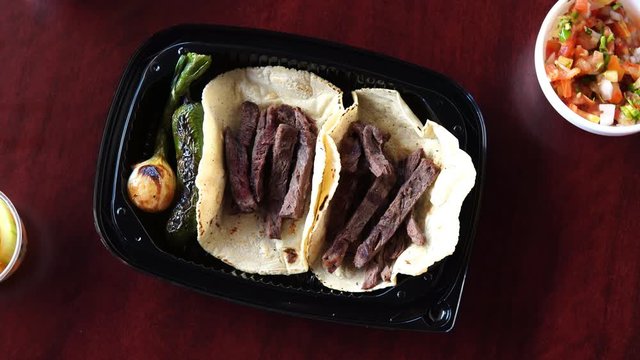 Tacos in corn tortillas accompanied by cambray onion and roasted jalape&ntilde;o on a dark wooden table. view from above