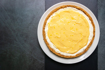 Delicious homemade honey lemon cheese pie and juicy lemon curd on plate with copy space on black...