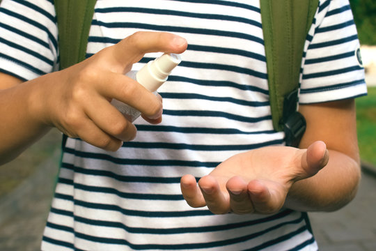 Boy using sanitizer or disinfectant spray for disinfecting hands at school. Back to school after coronavirus quarantine, pandemic prevention and new normal concept