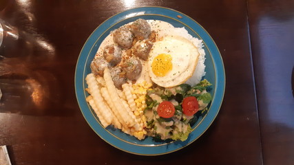Meatballs, French fries, salad, fried eggs, and rice