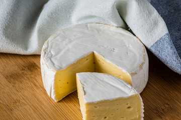 Fresh Brie cheese and a slice close up on wooden board