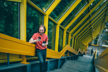 Fototapeta na wymiar Man standing on stairway of pedestrian bridge and smiling at phone