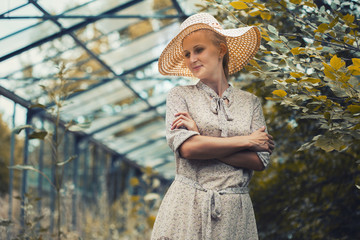 woman flowers in a retro dress and a hat in a old greenhouse