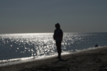 Fototapeta na wymiar silhouette of a girl on the beach blurred