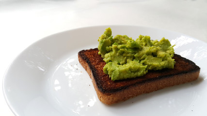 Baked toast with avocado on a white plate. Vegan food.	
