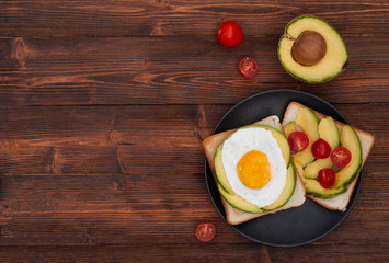 Healthy breakfast toasts with avocado and fried egg on the brown wooden background flat lay mock-up with copy space