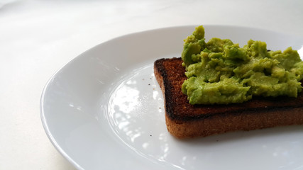 Baked toast with avocado on a white plate. Vegan food.	
