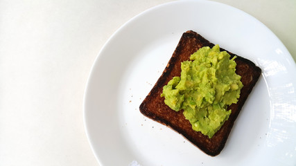 Baked toast with avocado on a white plate. Vegan food.	
