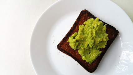 Baked toast with avocado on a white plate. Vegan food.	
