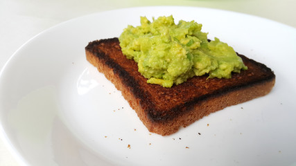 Baked toast with avocado on a white plate. Vegan food.	
