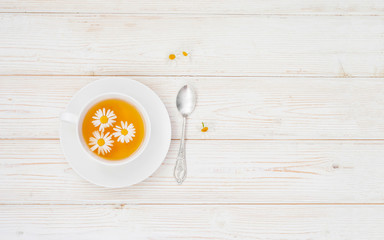 Fototapeta na wymiar Cup of herbal tea with honey and chamomile flowers on the white wooden background flat layout